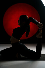 Athletic woman doing yoga in the studio and posing against the backdrop of light illuminations in the background. Yoga and meditation concept