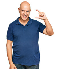 Middle age bald man wearing casual clothes smiling and confident gesturing with hand doing small size sign with fingers looking and the camera. measure concept.