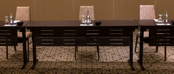 Empty convention center set up with tables, chairs, water, papers and pen for conference, business meeting, training course, lectures or seminars