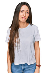 Obraz premium Young hispanic girl wearing casual white t shirt looking sleepy and tired, exhausted for fatigue and hangover, lazy eyes in the morning.
