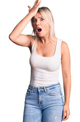 Young beautiful blonde woman wearing casual sleeveless t-shirt surprised with hand on head for mistake, remember error. forgot, bad memory concept.