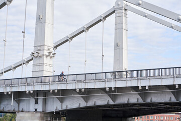 Man riding on bicycle across the bridge in the city.