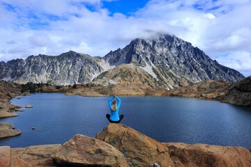 Woman meditating by blue mountain lake. Lake Ingalls. Leavenworth. WA. USA
