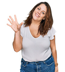 Young plus size woman wearing casual white t shirt showing and pointing up with fingers number five while smiling confident and happy.