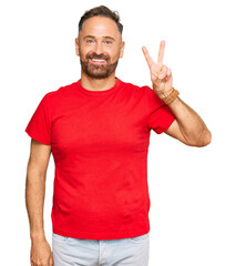 Naklejka premium Handsome middle age man wearing casual red tshirt showing and pointing up with fingers number two while smiling confident and happy.