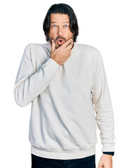 Middle age caucasian man wearing casual clothes looking fascinated with disbelief, surprise and amazed expression with hands on chin