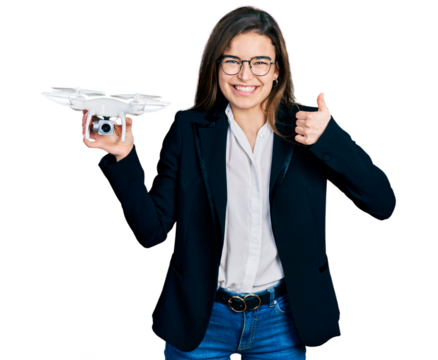 Young caucasian girl wearing business style holding drone smiling happy and positive, thumb up doing excellent and approval sign