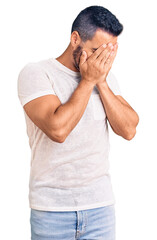 Young hispanic man wearing casual clothes with sad expression covering face with hands while crying. depression concept.