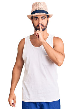 Young hispanic man wearing casual summer hat asking to be quiet with finger on lips. silence and secret concept.