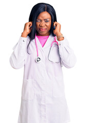 Young african american woman wearing doctor stethoscope covering ears with fingers with annoyed expression for the noise of loud music. deaf concept.