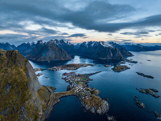 aerial view from the sea over reine fisherman  village on lofoten islands in norway during sunrise with mountains with snow on backgorund