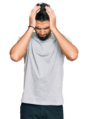 Fototapeta premium Young man with beard wearing casual grey tshirt suffering from headache desperate and stressed because pain and migraine. hands on head.