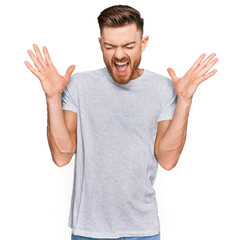 Fototapeta premium Young redhead man wearing casual grey t shirt celebrating mad and crazy for success with arms raised and closed eyes screaming excited. winner concept