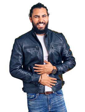 Young arab man wearing casual leather jacket smiling and laughing hard out loud because funny crazy joke with hands on body.