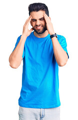 Fototapeta premium Young handsome man with beard wearing casual t-shirt with hand on head, headache because stress. suffering migraine.