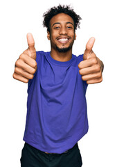Young african american man with beard wearing casual purple t shirt approving doing positive gesture with hand, thumbs up smiling and happy for success. winner gesture. - obrazy, fototapety, plakaty
