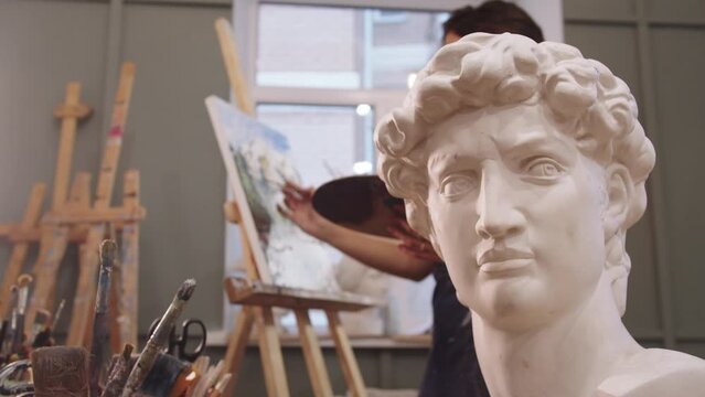 A Statue of a Man with a Hat On, Capturing the Essence of a Young Woman Painter Artist in Studio