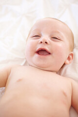 Happy baby on bed, funny and top view of young child in development, innocent or relax at home. Kid...