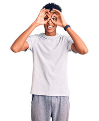 Young african american man wearing casual clothes doing ok gesture like binoculars sticking tongue out, eyes looking through fingers. crazy expression.