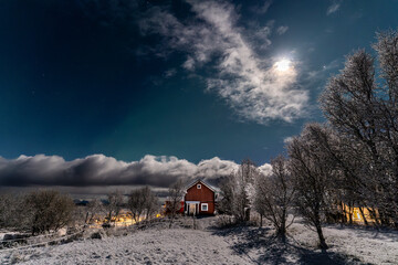 red house of norwegian scandinavian farm during winter night under the bright moon and northern...