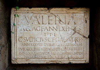 Roman inscription in marble from a funerary tombstone of Publius Valerius Laetus, which reads: Licensed soldier, 80 years old. Here it lies. May the earth be light to you.in Mérida Columbarios, Spain. - obrazy, fototapety, plakaty