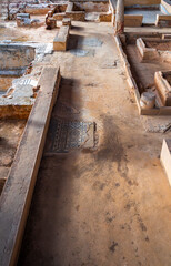 Archaeological remains of a hallway, rooms and Roman columns with remains of mosaics with blue geometric figures decorating the floors of the Mitreo house in Mérida, Spain.