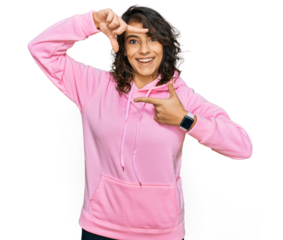 Young hispanic woman wearing casual sweatshirt smiling making frame with hands and fingers with happy face. creativity and photography concept.