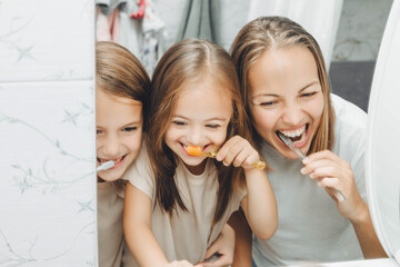 Mother and children brush their teeth in the bathroom. - obrazy, fototapety, plakaty