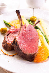 Traditional barbecue carree of venison with fruits, green and with asparagus served as close-up on...