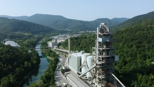 Aerial Orbit Around Salonit Anhovo Alpacem, Cement, Concrete and Aggregates Factory With Emerald Soca River Floating Beside, Surrounded With Forest, Solkan. Slovenia.