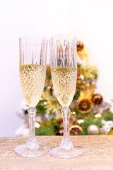 Crystal glasses with champagne against the backdrop of a festively decorated Christmas tree, close-up. New Year's Eve
