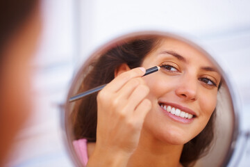Mirror, makeup and happy woman with eyeliner, pencil or application in a home bathroom with morning routine. Face, beauty and female person with eye, color or shape, aesthetic or cosmetic treatment