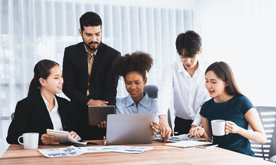 Multiracial analyst team use BI dashboard data to analyze financial report on meeting table. Group of diverse business people utilize data analysis by FIntech for success business marketing. Concord