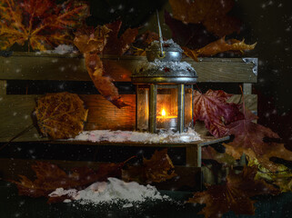 Burning candle in a lantern. Snow falls