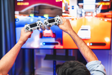 Close up photo of holding joystick crashing or cheerful friends on car racing competition of video game on blurred screen. Concept of lifestyles gamer on weekend with friend in living room. Sellable. © InfiniteFlow