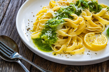 Tagliatelle with basil pesto sauce on wooden table