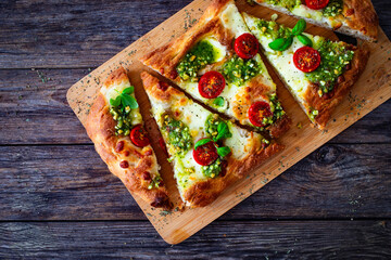 Pinsa Romana with mozzarella cheese and basil pesto on wooden table
