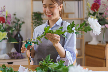 Florist concept, Woman florist cutting stem of chrysanthemum with pruning scissors in flower shop