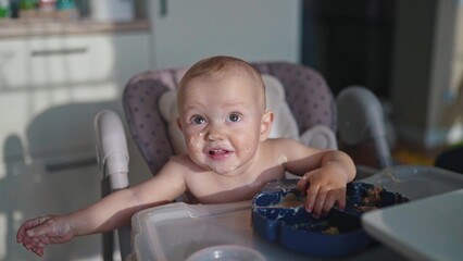 baby dirty eats. happy family a child toddler concept. baby dirty sitting messing with food at the...