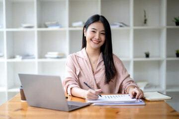 Asian businesswoman sitting work with laptop thinking about project planning. Analyzing marketing or financial data.