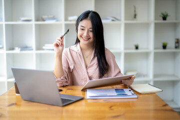Asian businesswoman sitting work with laptop thinking about project planning. Analyzing marketing or financial data.