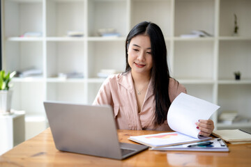Asian businesswoman sitting and working check documents analyze market reports. Review and compare report data.