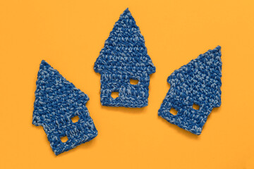 Three blue mini crochet houses on a yellow background. Top view. Copy space.