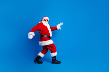 Fototapeta na wymiar Full length photo of mature pensioner man sneak go deliver gifts wear trendy santa claus costume coat isolated on blue color background