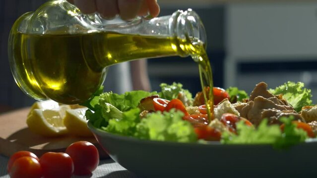 fresh chicken ceasar salad with crisp Romaine lettuce leaves and olive oil. olive oil pouring, organic vegetables. extra virgin olive, salad dressing, tomatoes, lemon