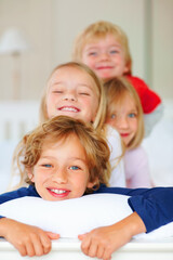 Portrait, smile or love with brother and sister sibling children on a bed in their home together. Family, happy or bonding with young boy and girl kids in the bedroom of an apartment on the weekend