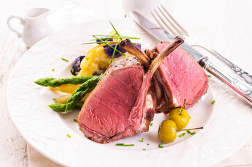 Traditional barbecue carree of venison with potato salad and green asparagus served as close-up on...