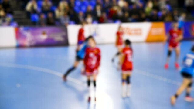 A women's sports team plays indoor handball. Blurry.
