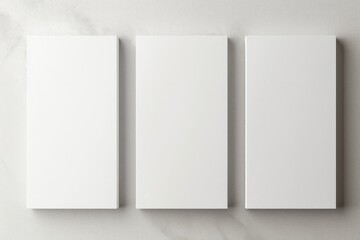 Three empty white vertical rectangle poster mockups. Flat lay, top view. Three Blank White Rectangle Picture Frames on a Wall - obrazy, fototapety, plakaty