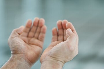 Close-up of a Muslim man praying with hands up in the air in the mosque, Religion praying concept